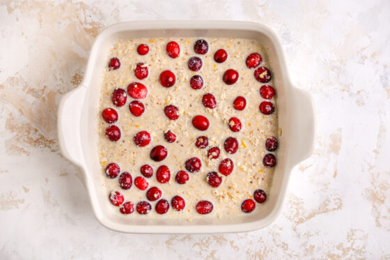 A baking dish with cranberry orange oatmeal mixture, topped with whole cranberries.