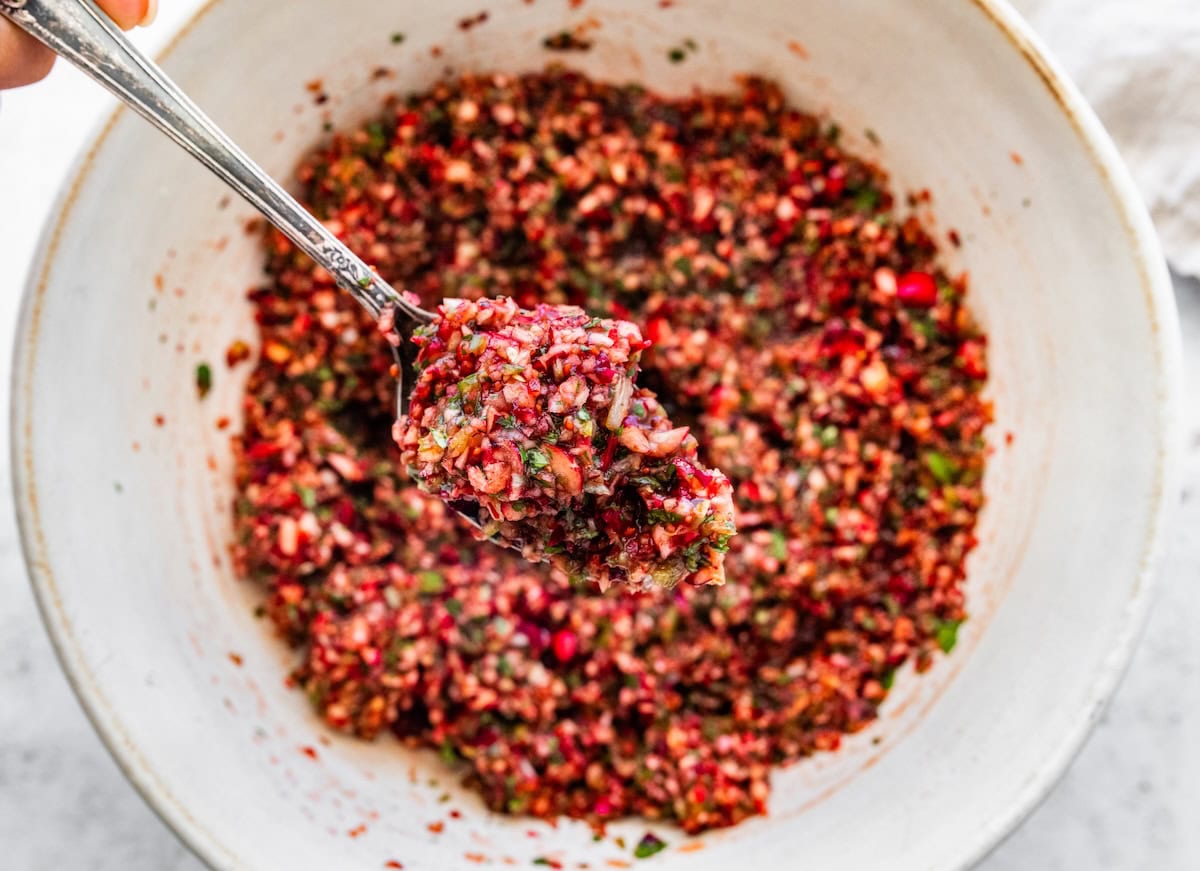 Cranberry salsa mixture in a white mixing bowl before chilling.