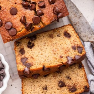 Almond flour banana bread with chocolate chips cut in two slices on a wire rack.
