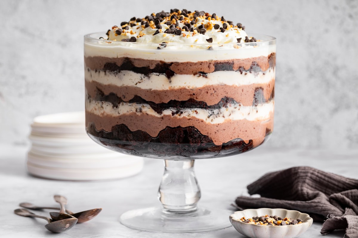 Layered high-protein death by chocolate trifle in a glass dish with brownies, pudding and whipped topping.