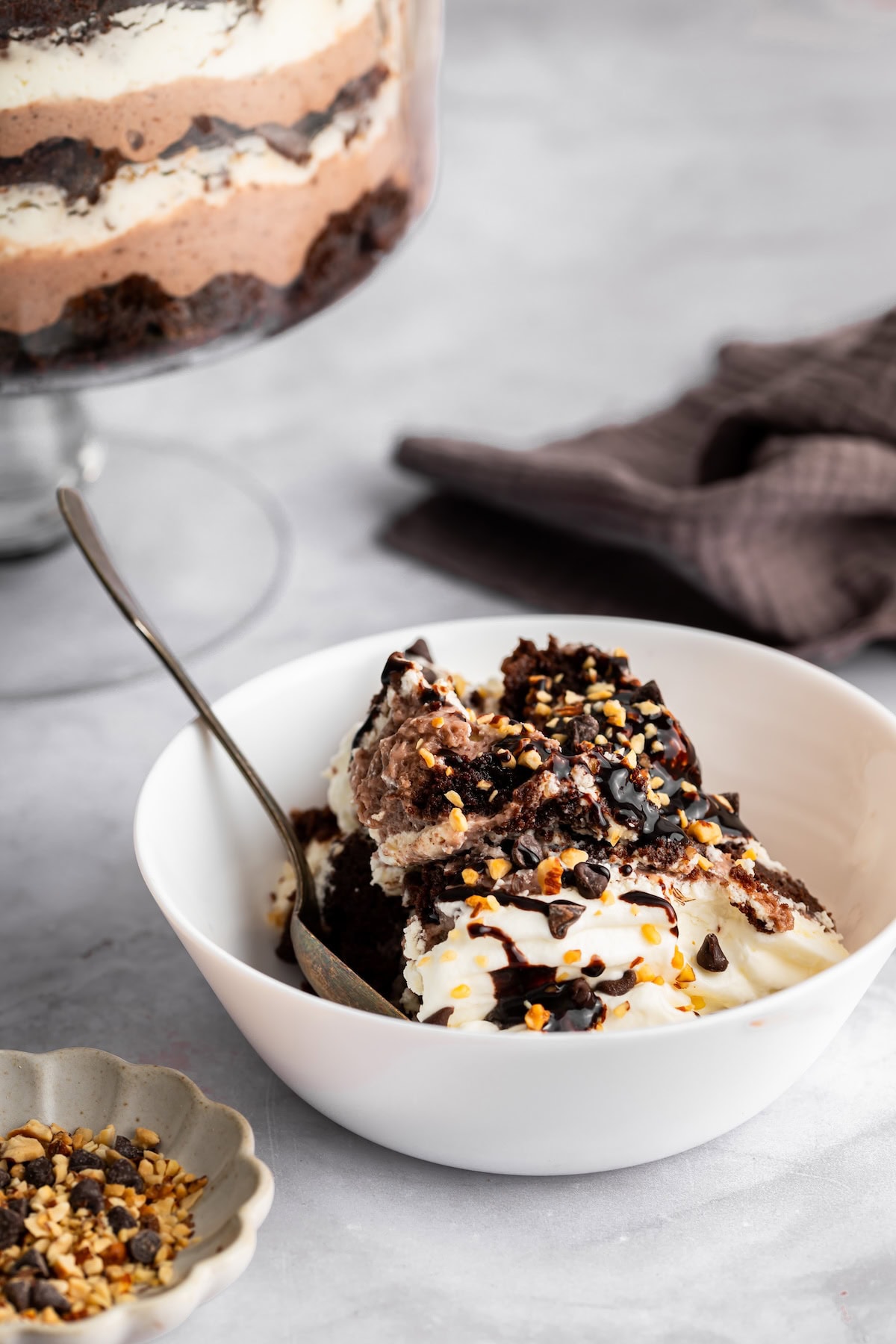 Scoop of death by chocolate trifle in a white bowl topped with whipped cream and drizzle.