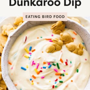 A bowl of creamy Dunkaroo dip topped with colorful sprinkles and bunny-shaped animal crackers, with text highlighting it as a high-protein snack.