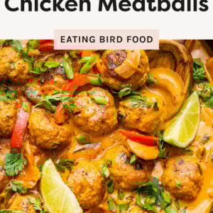 A skillet filled with Thai chicken meatballs simmering in a creamy, orange-colored curry sauce.