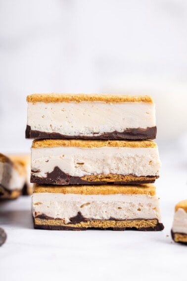 Three frozen s’mores bars stacked on top of each other showing distinct graham cracker, chocolate, and whipped protein layers.