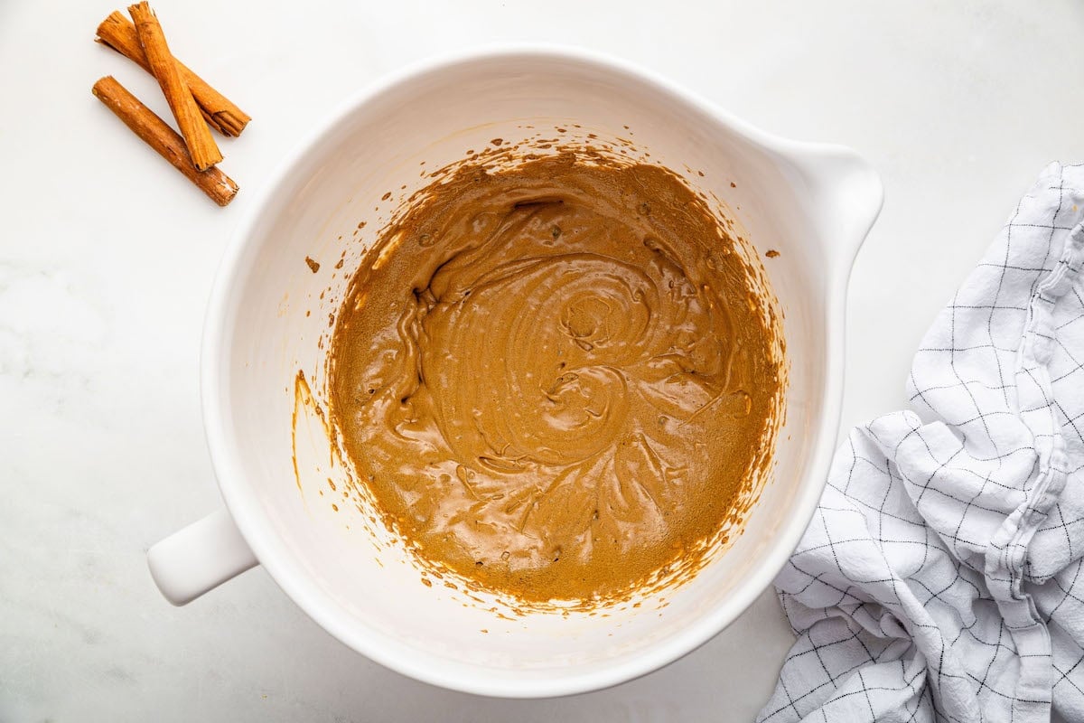 A large. mixing bowl of wet ingredients used to make gingerbread cookies.