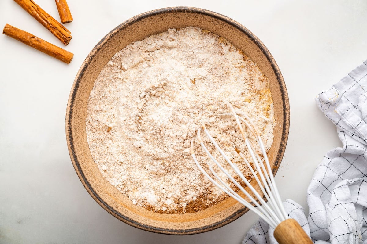 Dry ingredients used for gingerbread cookies in a large mixing bowl with a whisk.