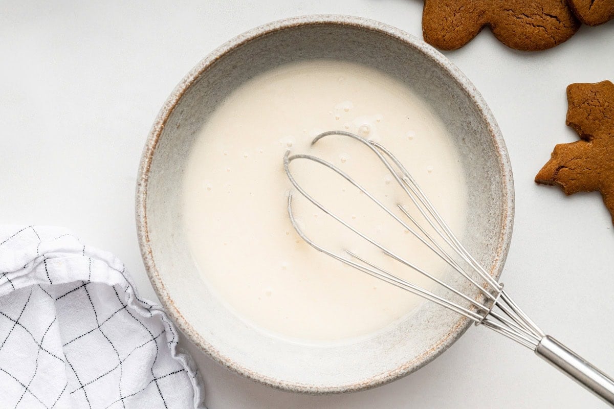 Icing being whisked in a small bowl that will be used for gingerbread cookies.
