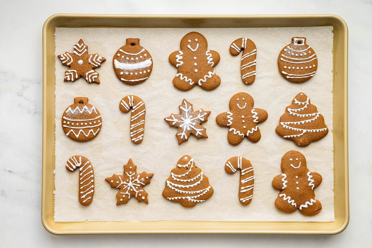 Gingerbread cookies decorated with icing on a baking tray.