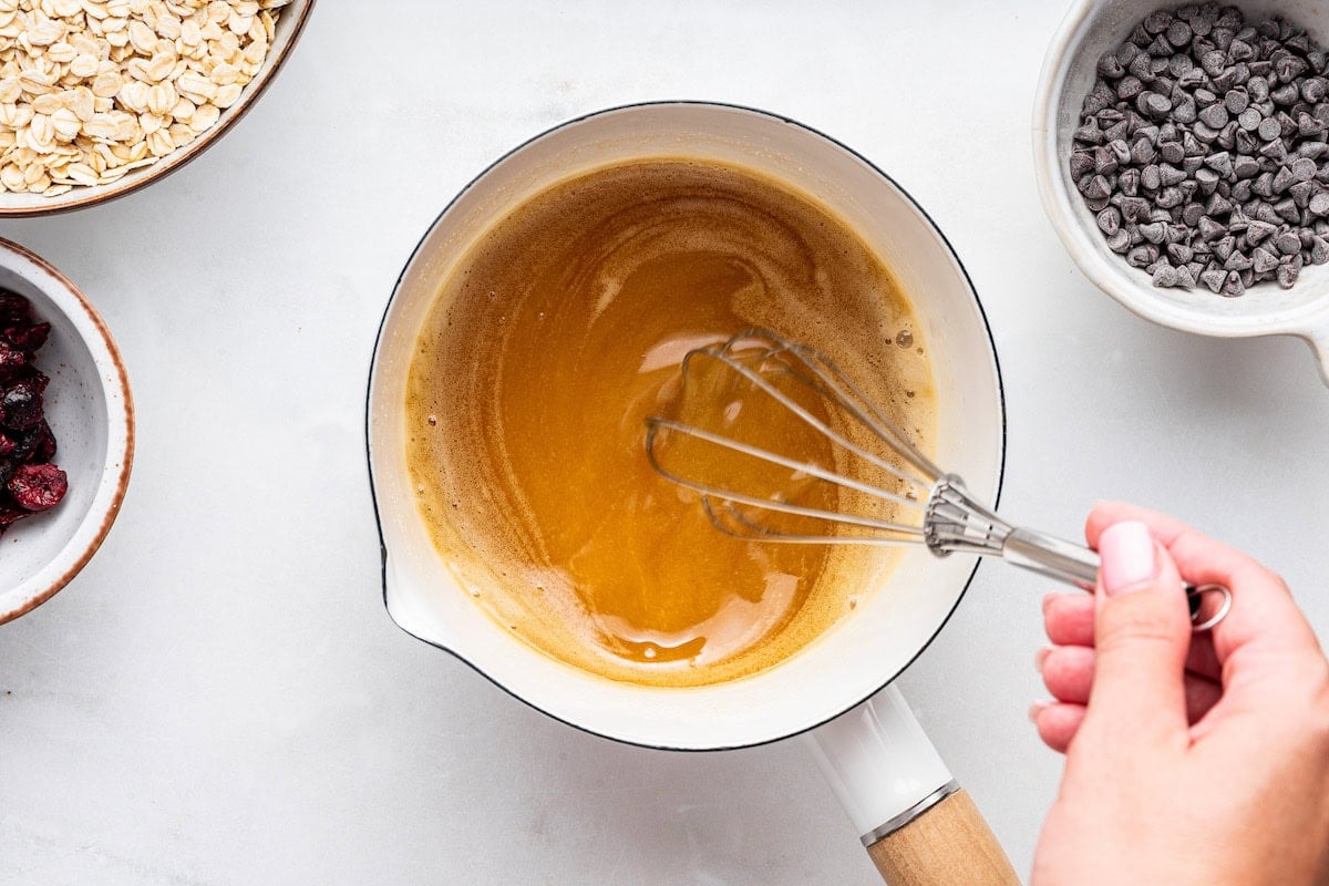 A womans hand uses a whisk to combine the butter, honey, sugar, cinnamon, and salt.