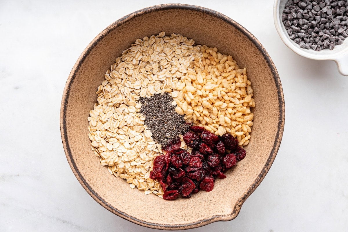 A large mixing bowl of rice cereal, rolled oats, chia seeds, and dried cranberries.