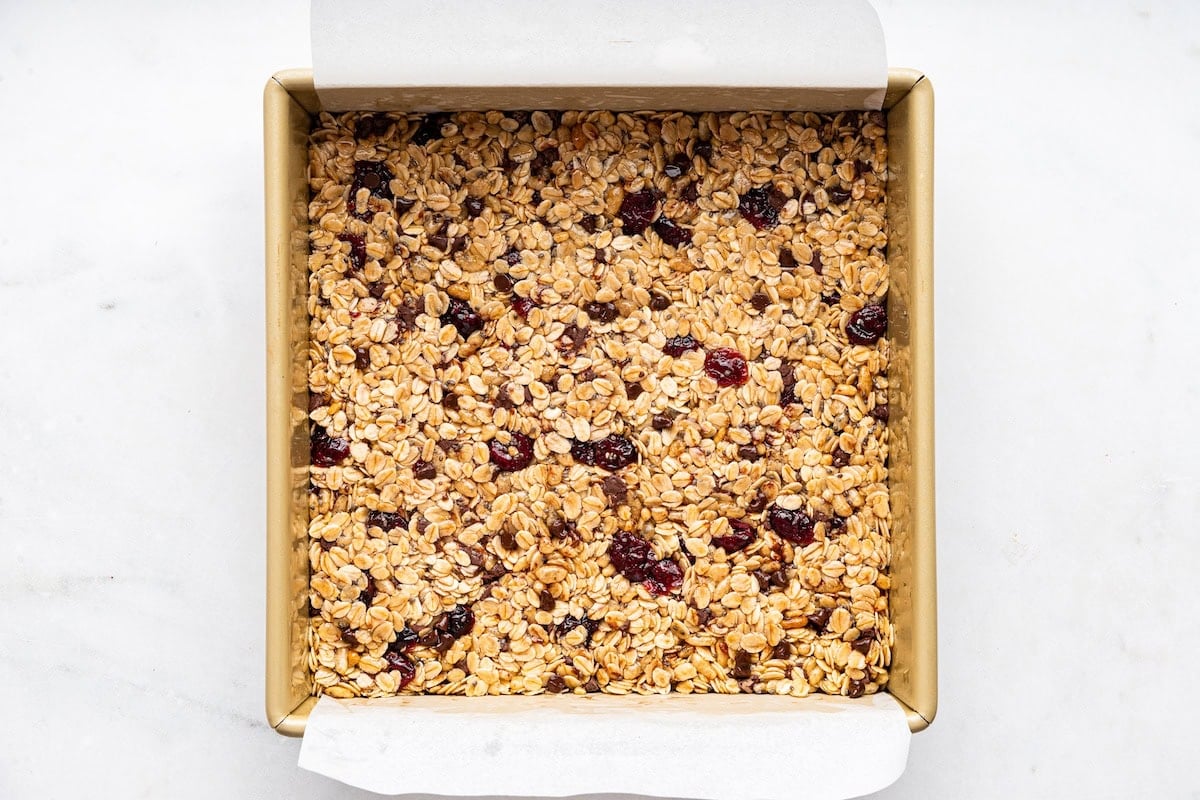 The granola bar mixture is placed and set into a square baking dish.