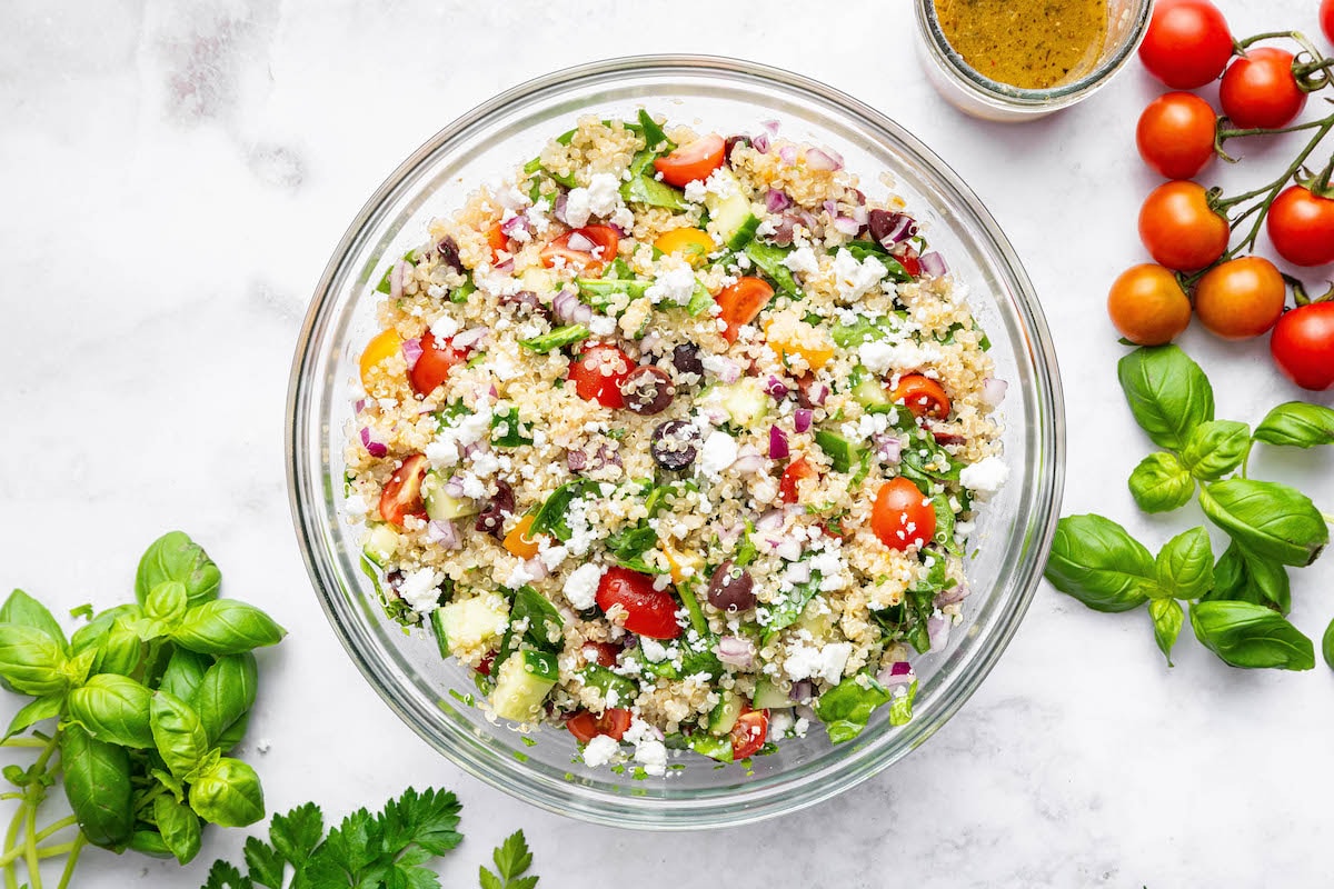 The mixed together Greek quinoa salad in a glass bowl.
