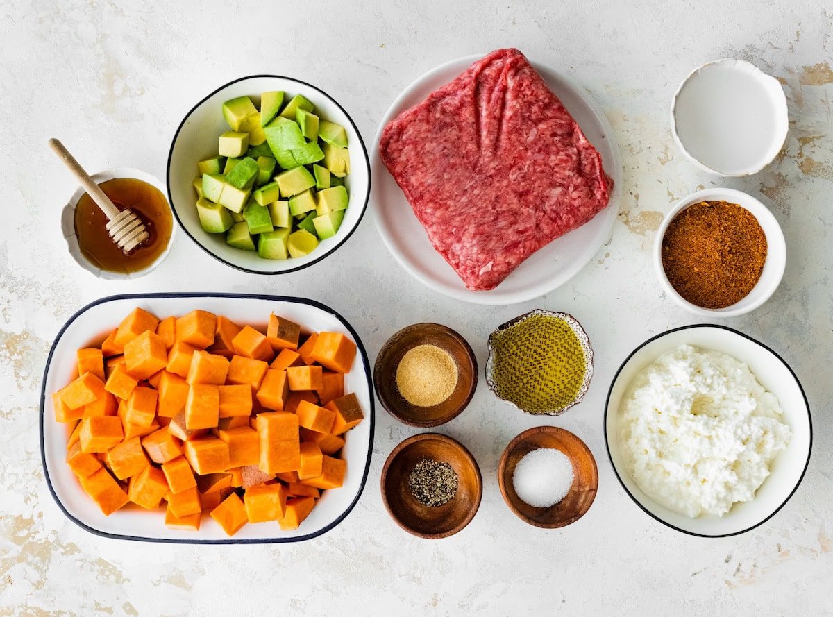 Ingredients measured out to make Ground Beef Cottage Cheese Sweet Potato Bowl: Sweet potato, hot honey, avocado, pepper, garlic powder, salt, olive oil, beef, cottage cheese, taco seasoning, water.