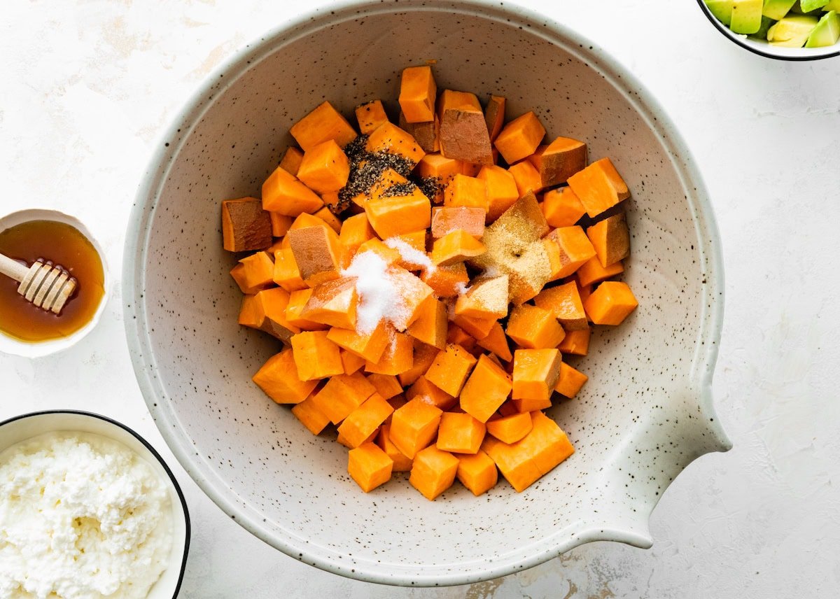 Cubed sweet potatoes in a mixing bowl with seasonings.