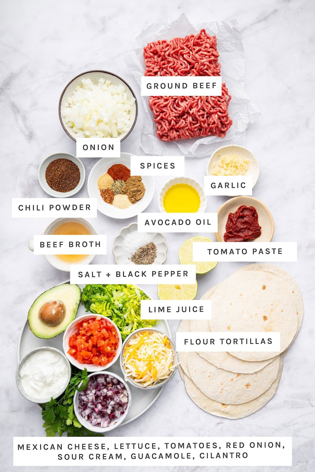 Ground Beef Taco ingredients: Ground beef, onion, garlic, avocado oil, tomato paste, beef broth, salt, black pepper, lime juice, flour tortillas, paprika, oregano, garlic powder, onion powder, cumin, red pepper flakes, chili powder, Mexican cheese, lettuce, tomatoes, red onion, sour cream, guacamole, cilantro.