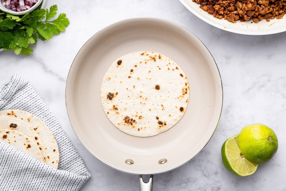 A small flour tortilla heating in a skillet.