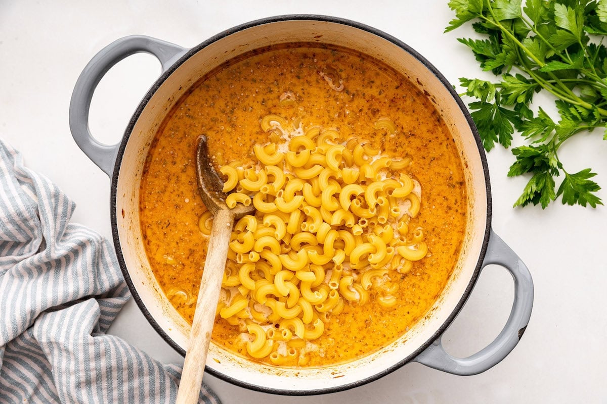 Macaroni noodles added to a large pot of other ingredients used for a healthy hamburger helper.