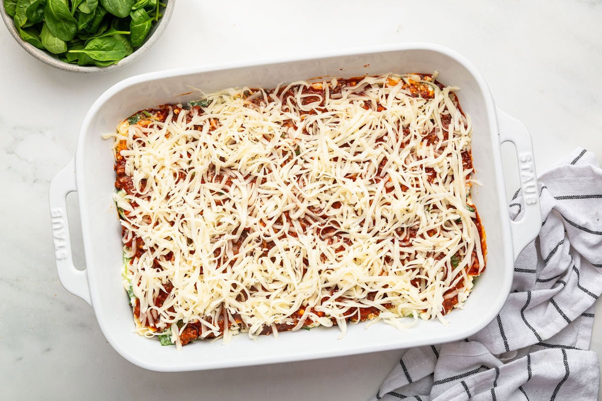Shredded cheese added to the top of the lasagna in a baking dish before being baked.