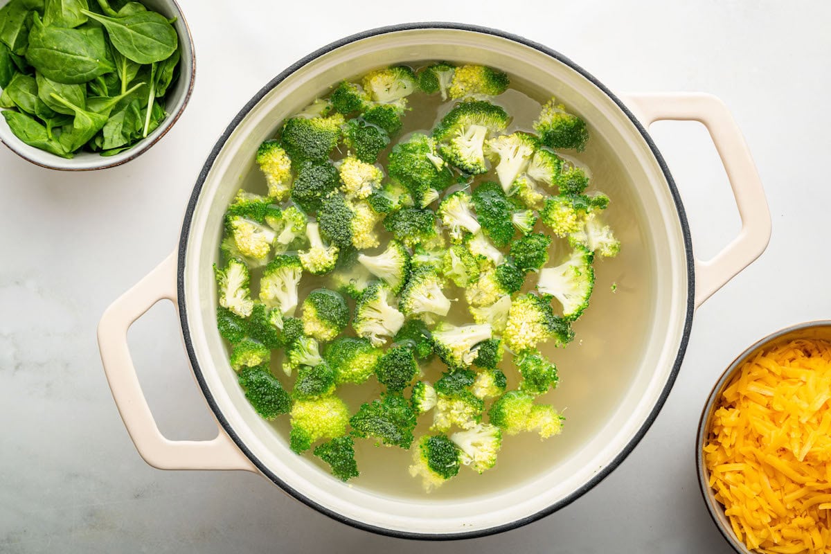 Broccoli florets cooking in a pot pot of boiling water with the rotini pasta.