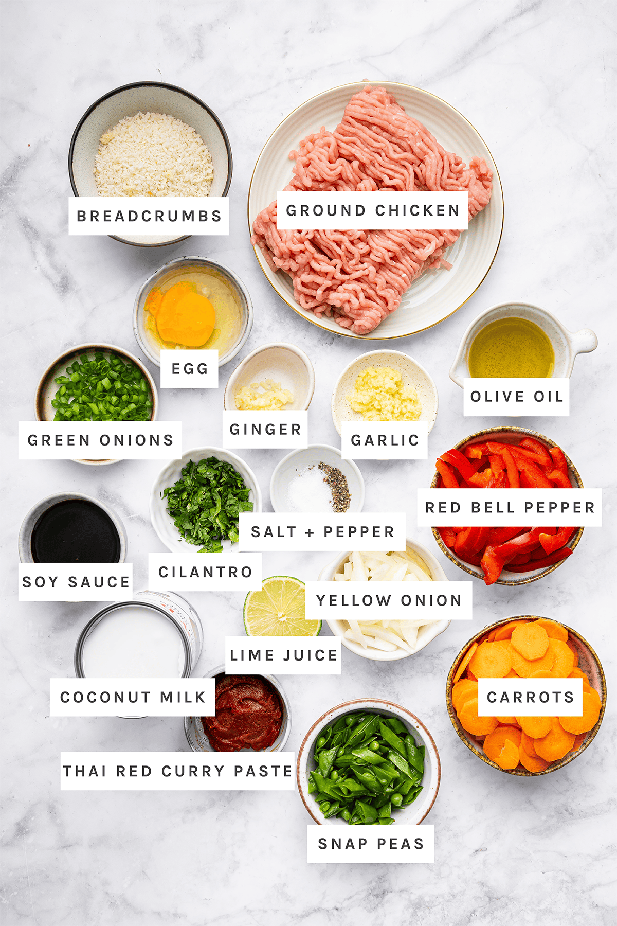 Ingredients measured out to make Thai Chicken Meatballs: Breadcrumbs, Ground Chicken, Egg, Ginger, Garlic, Olive Oil, Green Onions, Salt + Pepper, Red Bell Pepper, Soy Sauce, Cilantro, Yellow Onion, Lime Juice, Carrots, Coconut Milk, Thai Red Curry Paste, Snap Peas.
