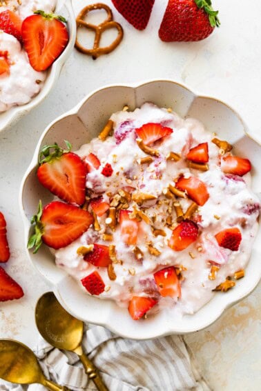 A bowl of strawberry pretzel salad topped with strawberries and crushed pretzels.
