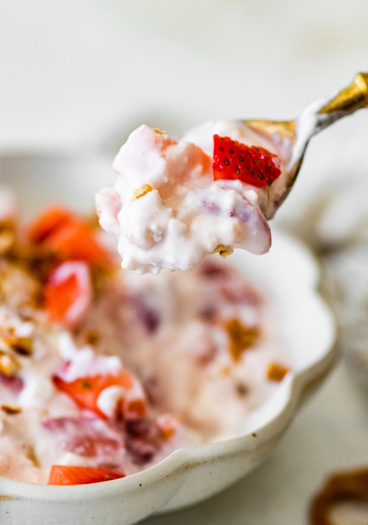 Close-up of a spoonful of strawberry pretzel salad with yogurt and cottage cheese.