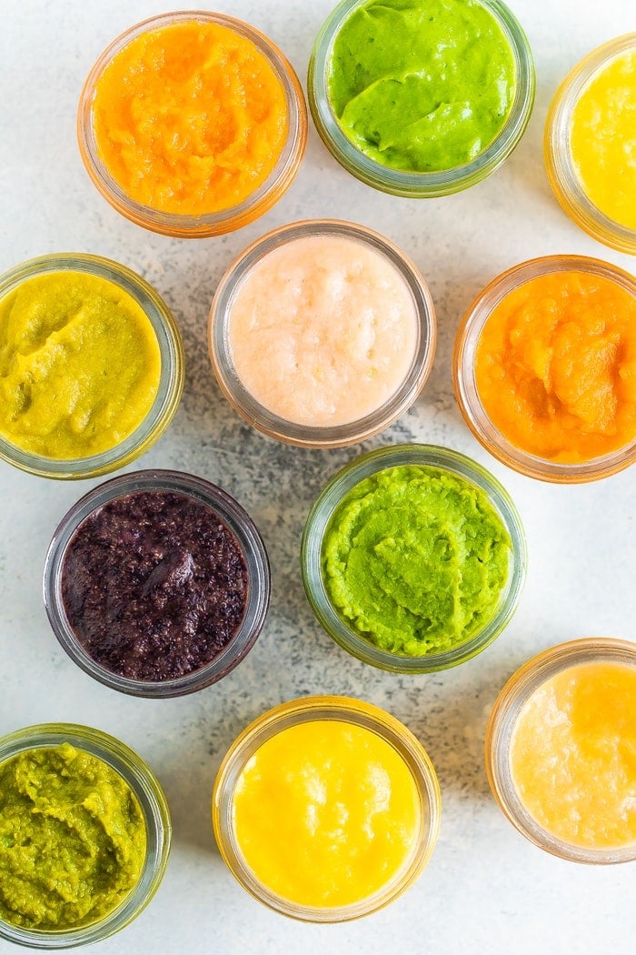 Overhead photo of glass baby food jars filled with 6 different types of homemade baby food.