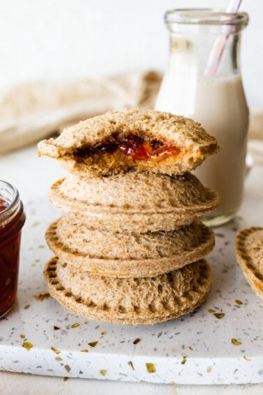 Four peanut butter uncrustables stacked on one another with the top having a bite taken from it.