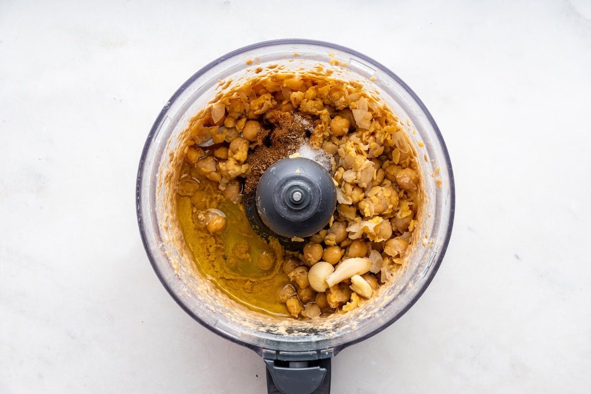 A food processor of tahini, garbanzo beans, garlic, salt, and spices.