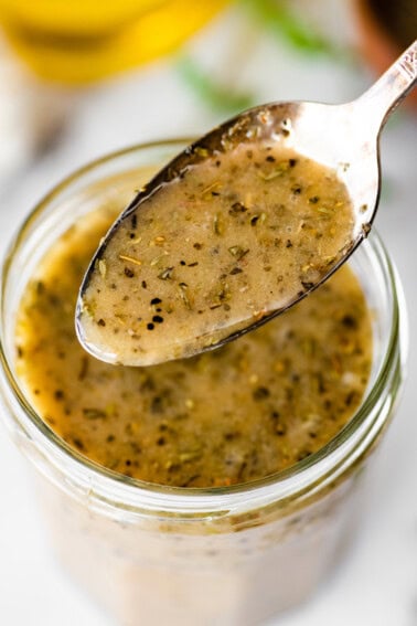 Spoonful of homemade Italian dressing showing herbs and texture.