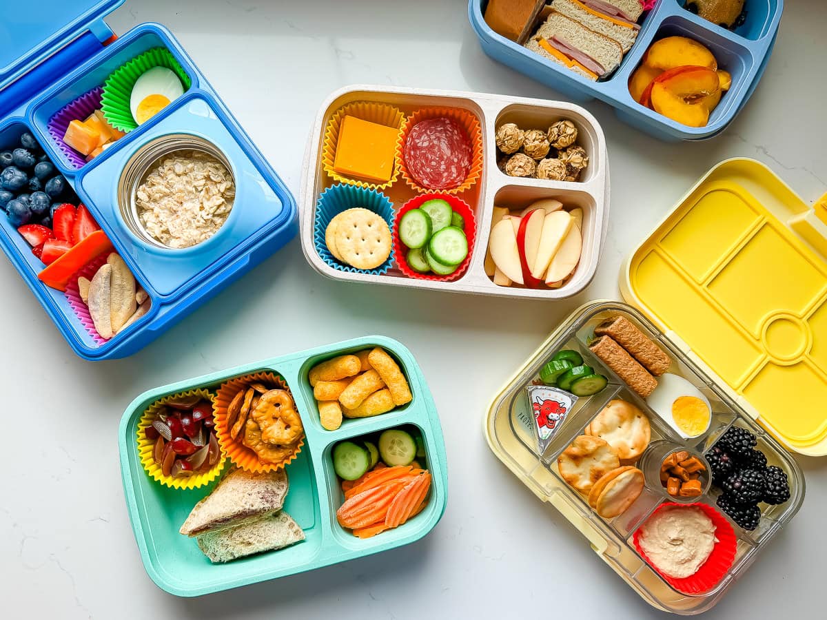 A countertop with 5 packed school lunches in different containers.