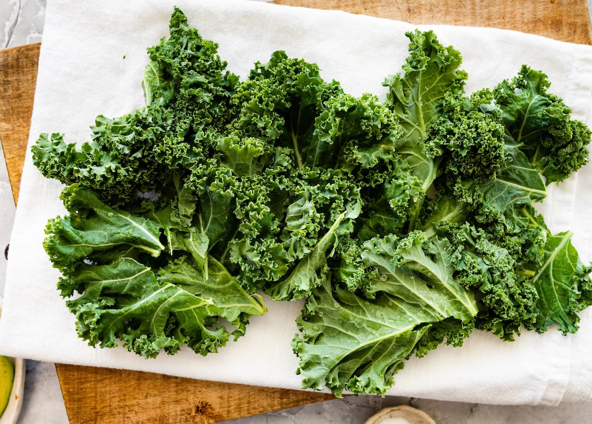 Fresh curly kale leaves drying on a white kitchen towel.