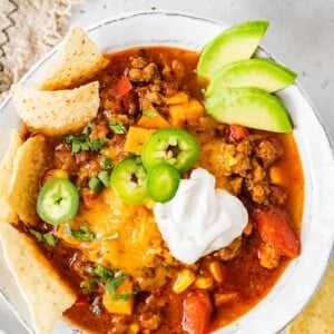A bowl of no bean chili topped with cheese, jalapeños, avocado, sour cream and chips.