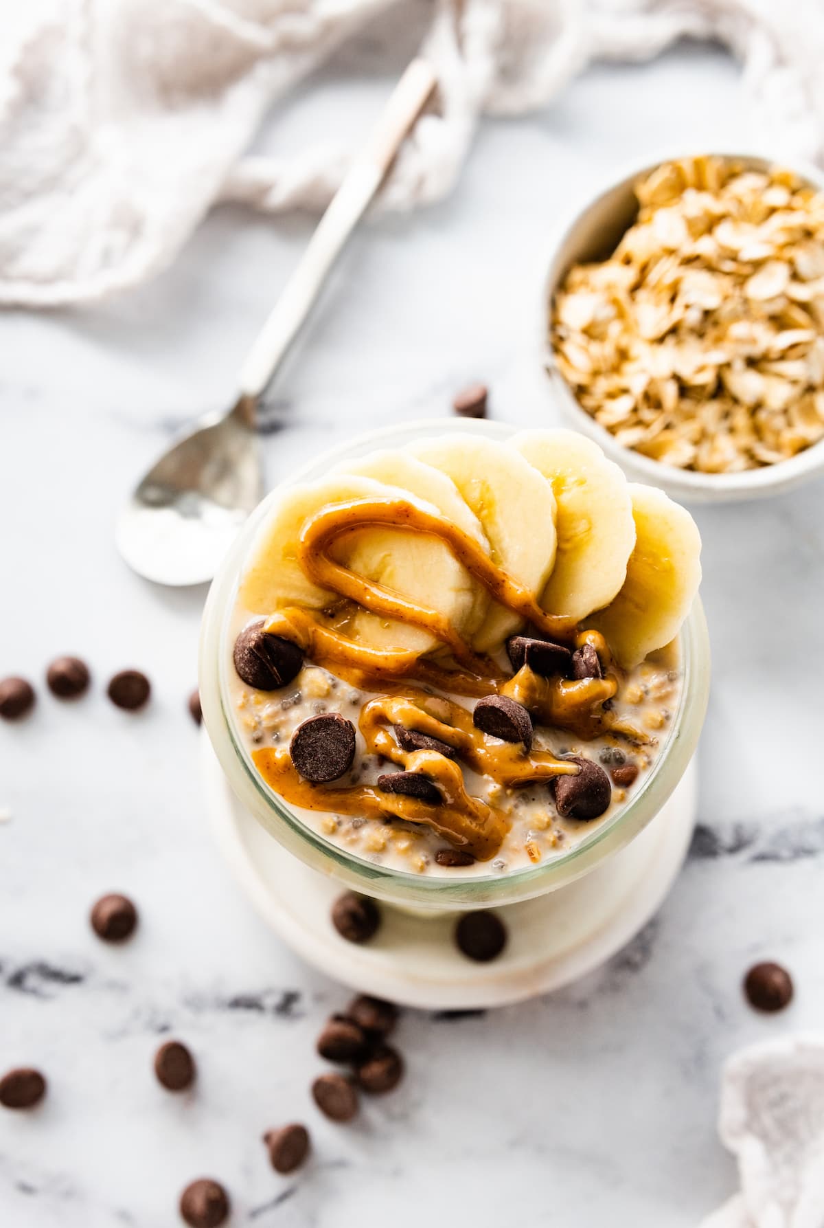 Overnight oats in a glass jar topped with fresh berries, nut butter, and nuts.