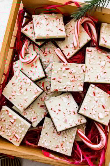 Square peppermint bark pieces stacked on top of each other in a gift box.