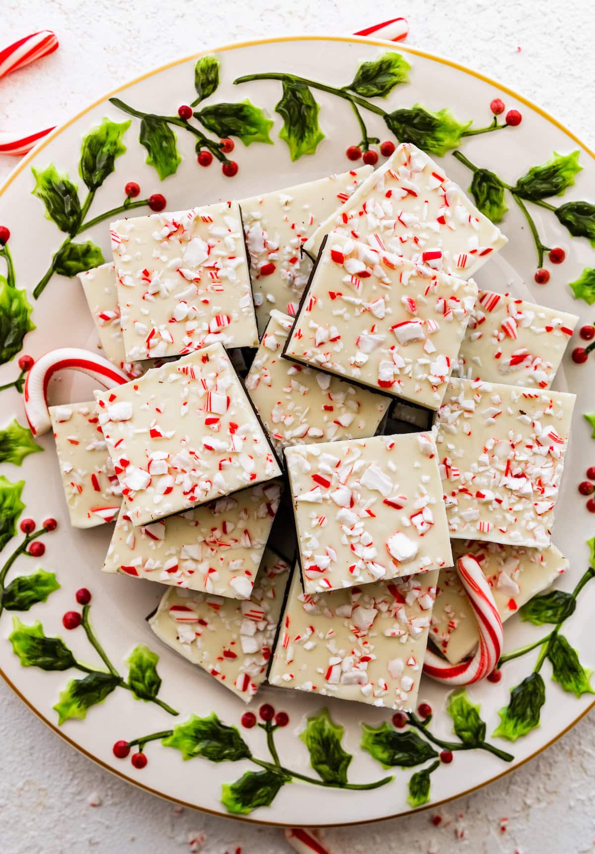 Square peppermint bark pieces stacked on top of each other on a Christmas plate.
