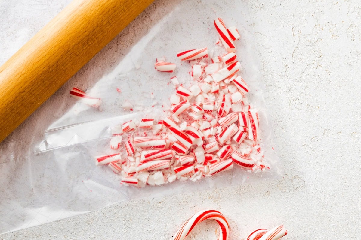 Crushed candy canes in a plastic bag with a rolling pin next to the bag.