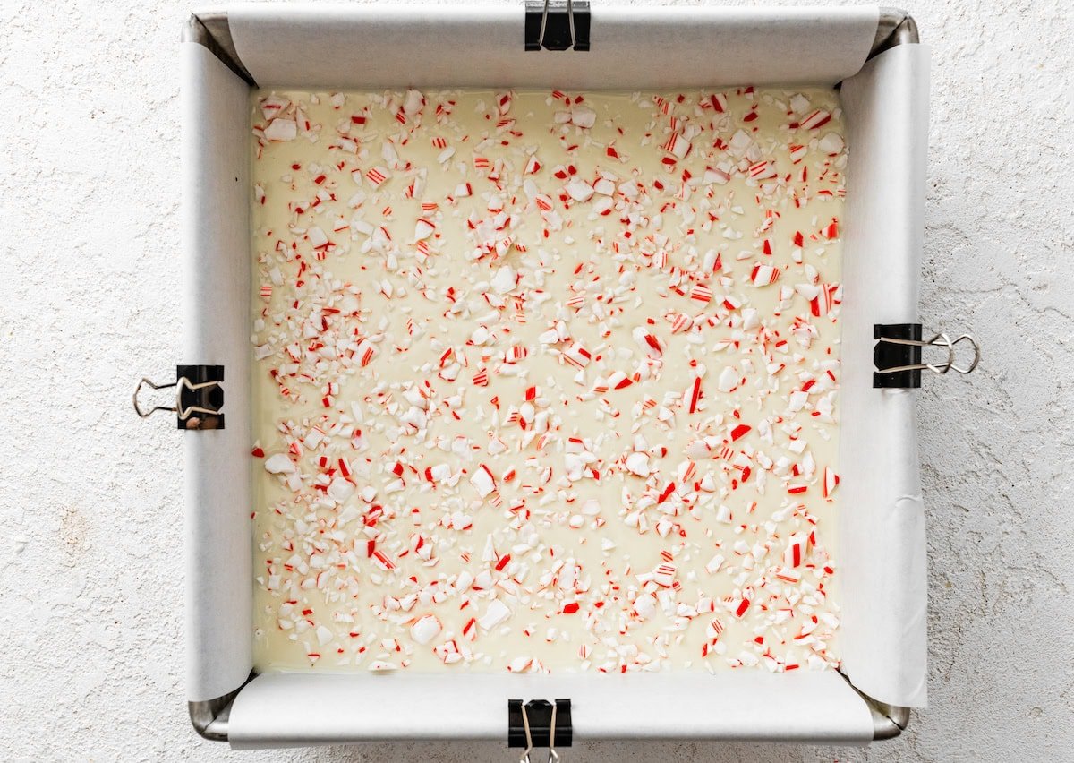 The peppermint bark topped with crushed candy canes in a square baking dish.