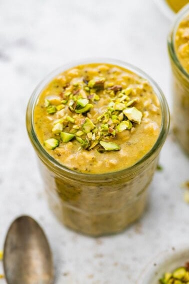 A jar of pistachio overnight oats topped with chopped pistachios.
