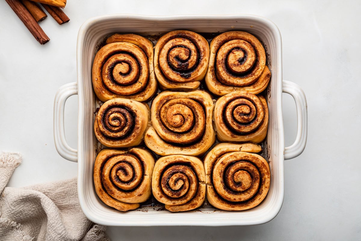 9 protein cinnamon rolls in a white square baking dish after being baked.