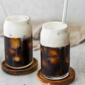 Two glasses of iced coffee with protein cold foam on top.