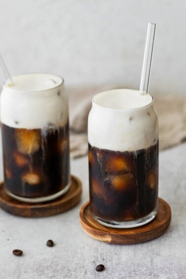 Two glasses of iced coffee with protein cold foam on top.