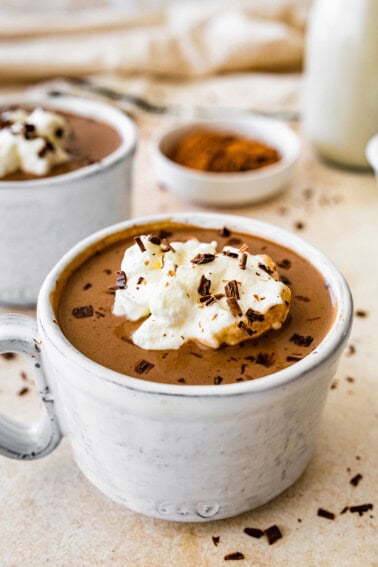 Protein hot chocolate in a white ceramic mug topped with whip cream and shaved chocolate.