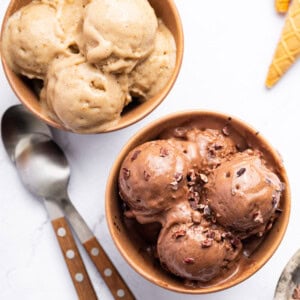Two bowls of protein ice cream-one is chocolate and one is vanilla. There are two spoons next to the bowls.