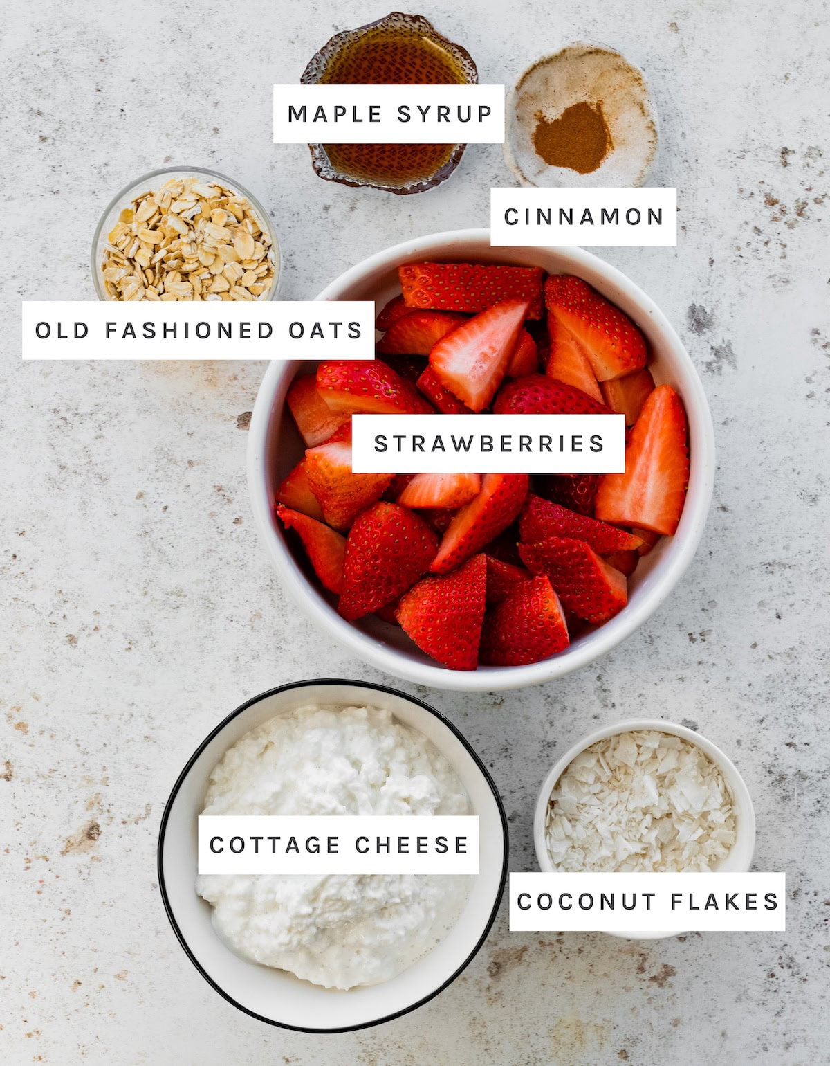 Roasted Strawberry Cottage Cheese Bowl ingredients: Strawberries, Cottage Cheese, Old Fashioned Oats, Maple Syrup, Cinnamon, Coconut Flakes.