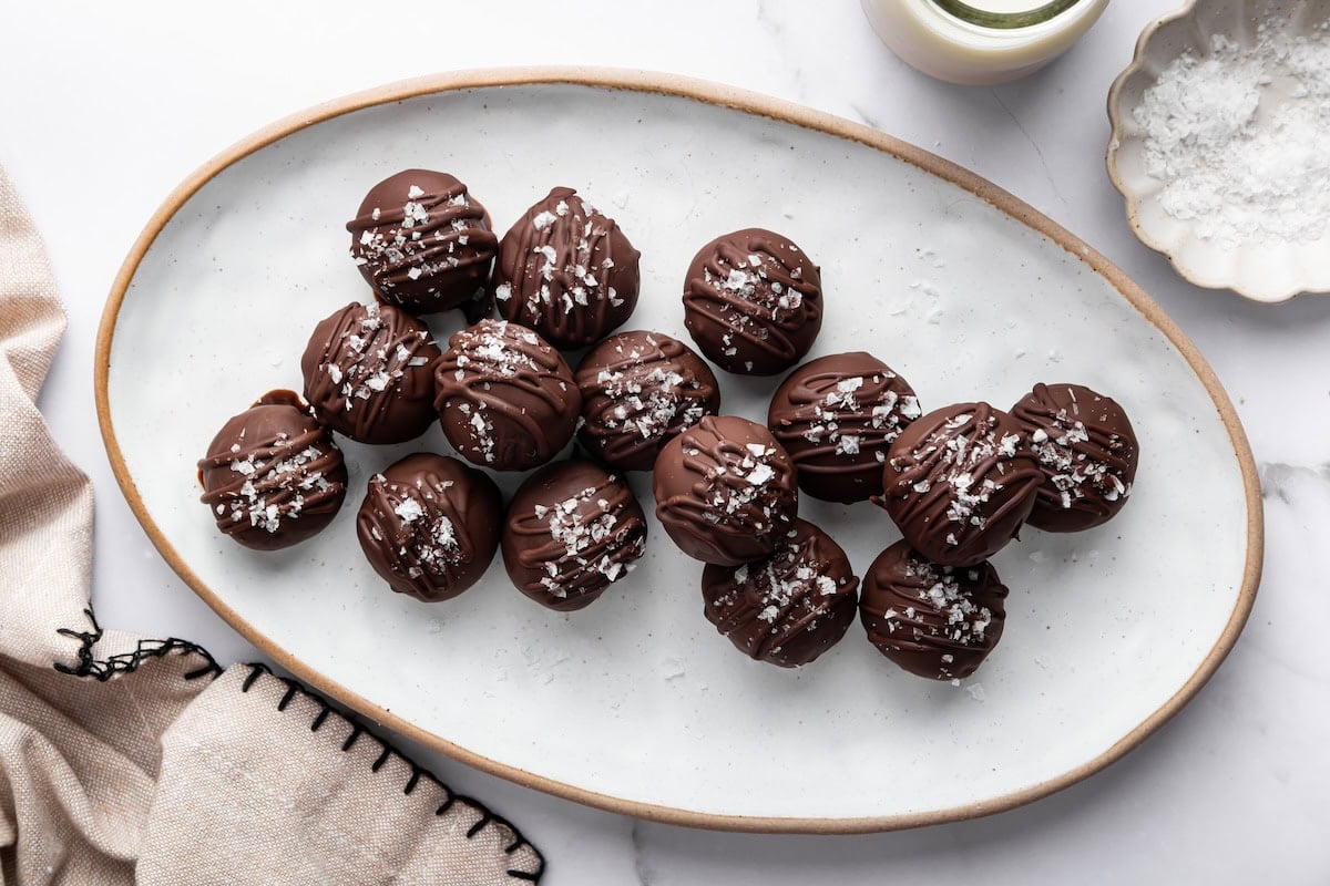 Platter of salted chocolate protein balls arranged neatly with a drizzle of chocolate and flaky salt.