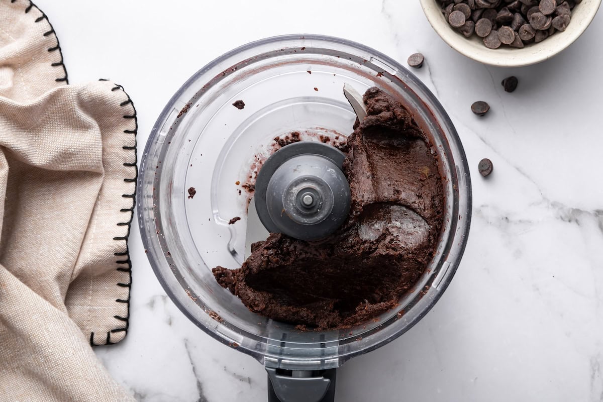 Food processor with blended chocolate protein ball mixture.