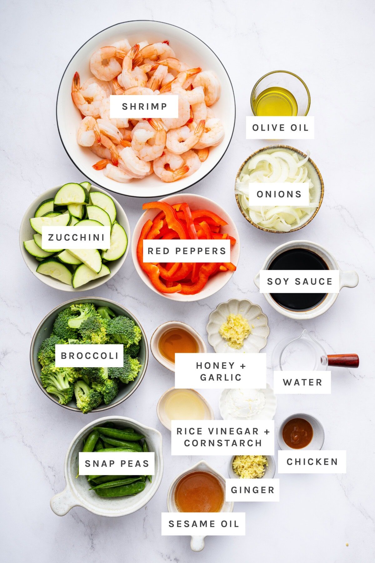 Ingredients measured to make Shrimp Stir Fry: Shrimp, olive oil, onions, soy sauce, water, chicken, ginger, sesame oil, rice vinegar + cornstarch, honey + garlic, snap peas, broccoli, zucchini, red peppers.