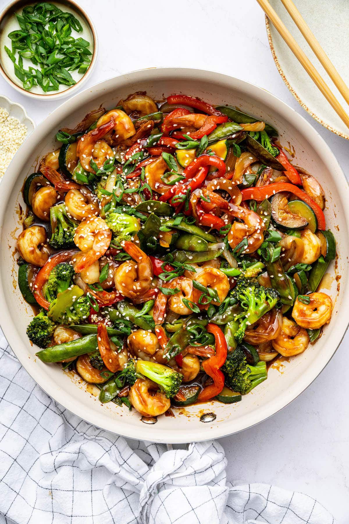 Shrimp stir-fry with shrimp, broccoli, red bell peppers, snap peas, zucchini, and onions coated in sauce.