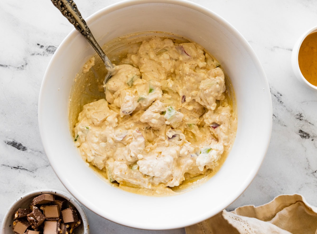 The Snickers salad protein bowl ingredients mixed together in a white mixing bowl.